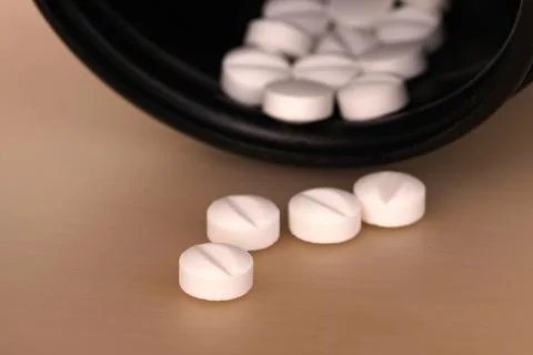 White pills on the table and a black bottle. Selective focus. Stock Photos