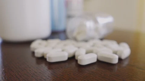 White pills on the table, slowly approaching the bottle, focus on macro close up Stock Footage 125636599