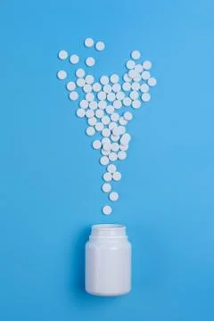 White pills, tablets and white bottle on blue background Stock Photos