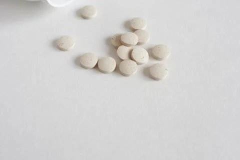 White pills on a white background. Focus on foreground, soft bokeh. Stock Photos