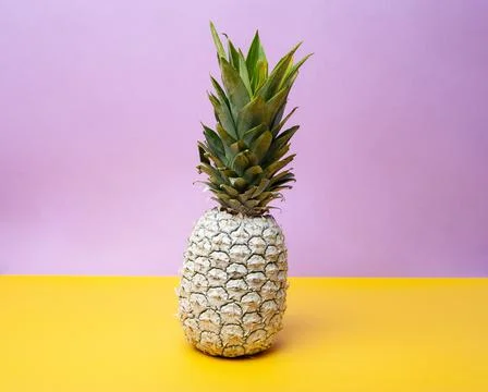 White pineapple on table in studio on violet and yellow background Stock Photos