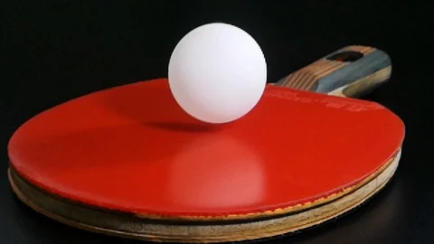 White ping pong balls bounce over red rubber racket.Slow motion Stock Footage 98356583