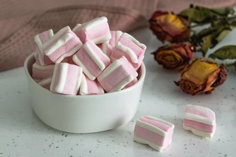 White-pink marshmallow on a light table next to a bouquet of wild field dried Stock Photos