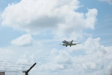 White Plane Approaching Runway with Cloudy Sky Background Stock Photos