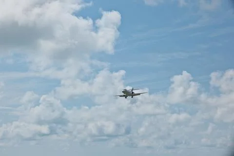 White Plane Approaching Runway with Cloudy Sky Background Stock Photos