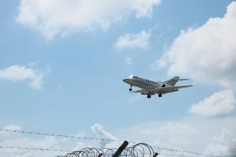 White Plane Approaching Runway with Cloudy Sky Background Stock Photos