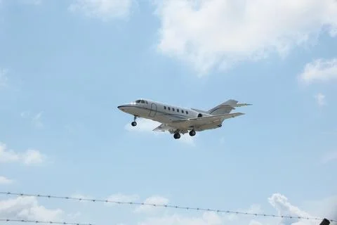 White Plane Approaching Runway with Cloudy Sky Background Stock Photos