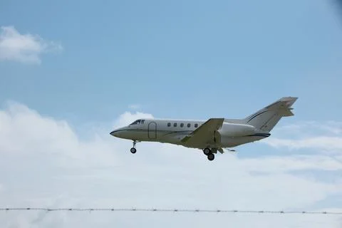 White Plane Approaching Runway with Cloudy Sky Background Stock Photos