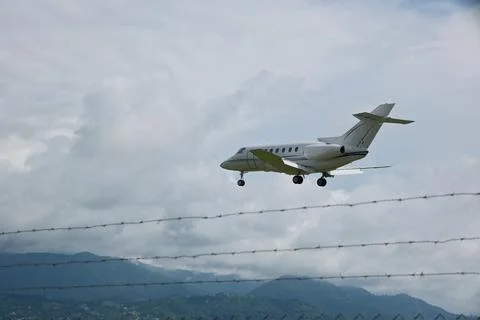 White Plane Approaching Runway with Cloudy Sky Background Stock Photos