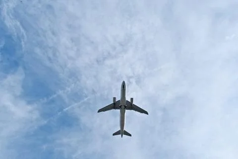 White Plane Overhead in Light Clouds. Stock-Fotos