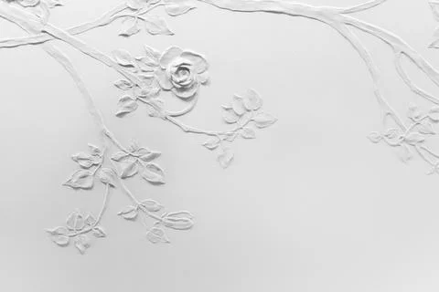White plaster wall with a delicate raised rose relief Stock Photos