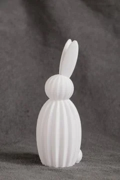 A white plastic 3D printed bunny figurine on gray fabric, themed around Eas.. Stock Photos