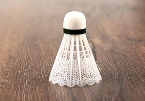 White plastic badminton shuttlecock vertically on a wooden background. Stock Photos