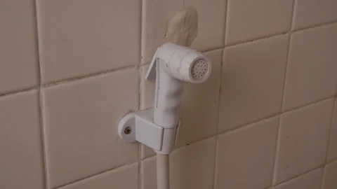 White plastic bidet hand shower sprayer on bathroom wall Видео 331706375