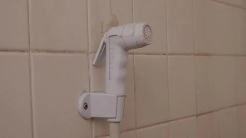 White plastic bidet hand shower sprayer on bathroom wall Stock Footage 334789940