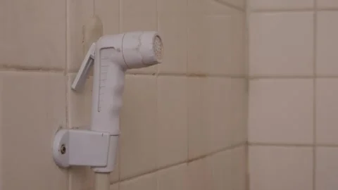 White plastic bidet hand shower sprayer on bathroom wall 库存影片 334789942