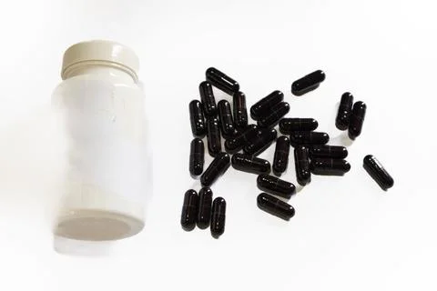 White plastic bottle with black capsules medication pills supplement Stock Photos