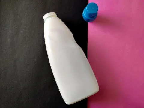 White plastic bottle with blue cap isolated on a pink and black background fo Stock Photos