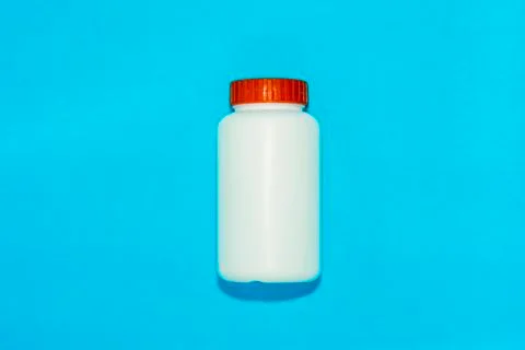 White Plastic Bottle  Container with red cap on Blue Background Stock Photos