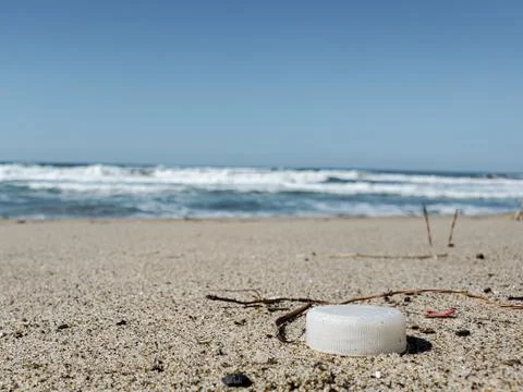 White plastic bottle cork on sandy sea coast, polluted ecosystem,microplastics Stock Photos