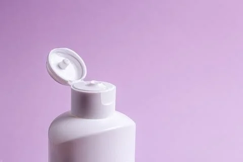 White plastic bottle with cream without label on a lilac background. Stock Photos