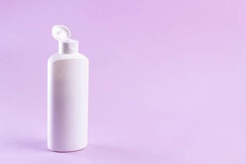White plastic bottle with cream without label on a lilac background. Stock Photos