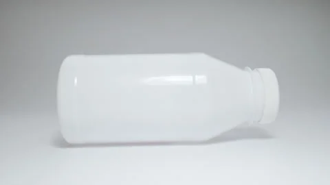 White plastic bottle with lid rolls on white surface. Stock Footage 149157590