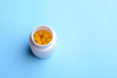 White plastic bottle with yellow ball pills inside Stock Photos
