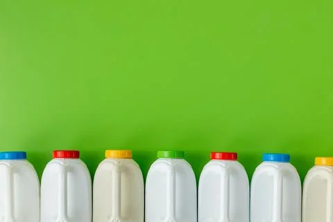 White plastic bottles with differently colored caps on a beautiful green  Stock Photos