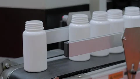 White plastic bottles fall from conveyor belt of blow molding machine - close up Vídeo Stock 337061365