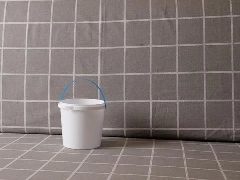 White plastic bucket with handle on sofa with checkered upholstery in minimal Photos