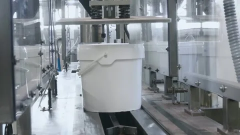 White plastic buckets moving through an advanced automated packaging line Stock Footage 336048723