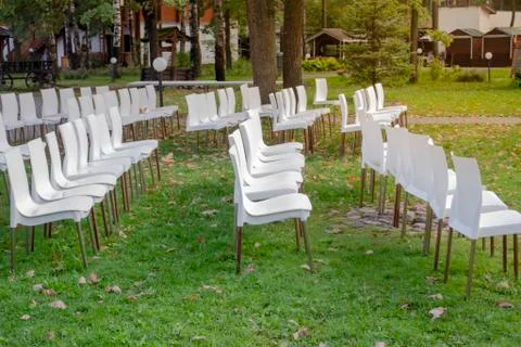 White plastic chairs in row stand waiting for visitors. Stock Photos