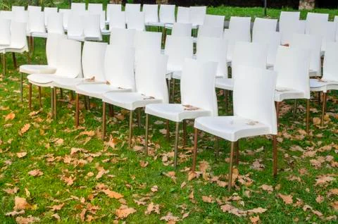 White plastic chairs in row stand waiting for visitors. Stock Photos