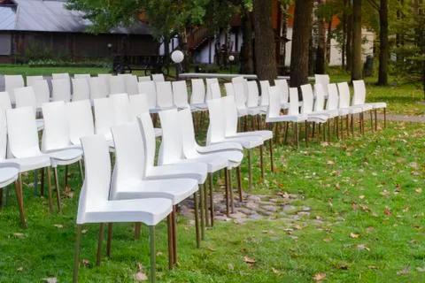 White plastic chairs in row stand waiting for visitors. Stock Photos