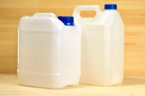 White plastic containers (gallon) on the background of wooden wall Stock Photos