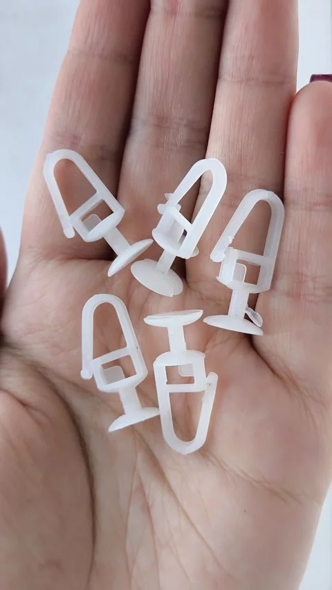 White plastic curtain hook with roller wheel held in hand Stock Footage 318130032