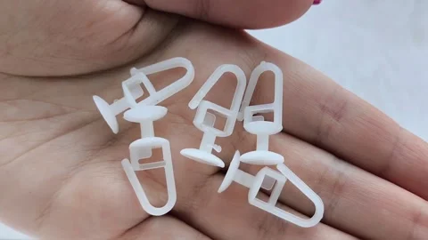 White plastic curtain hook with roller wheel held in hand Stock Footage 318130071