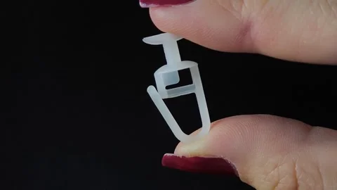 White plastic curtain hook with roller wheel held in hand Stock Footage 318130169