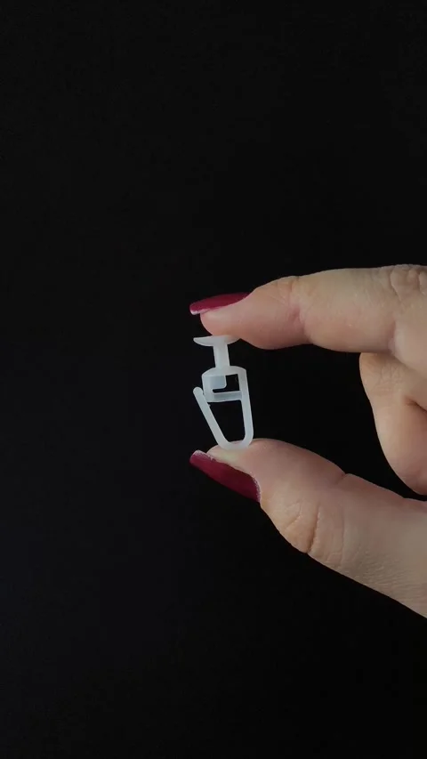 White plastic curtain hook with roller wheel held in hand Stock Footage 318130601