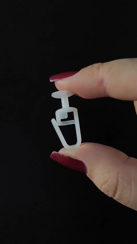 White plastic curtain hook with roller wheel held in hand Stock Footage 318130919