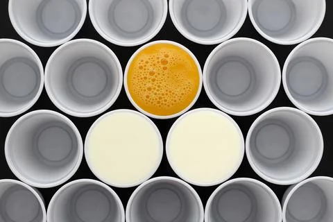 White plastic disposable cups filled with milk and orange juice Stock Photos