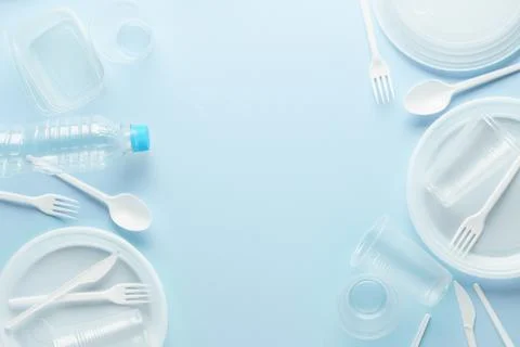 White plastic disposable tableware on blue background. Stock Photos