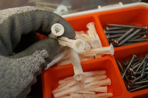 White plastic dowels in the hands of a builder. Stock Photos