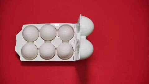 A white plastic egg container that holds 6 eggs on red background. Stop motion Stock Footage 297398277