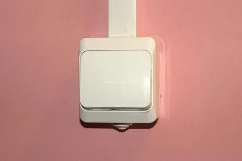White plastic electrical switch on a pink wall Stock Photos