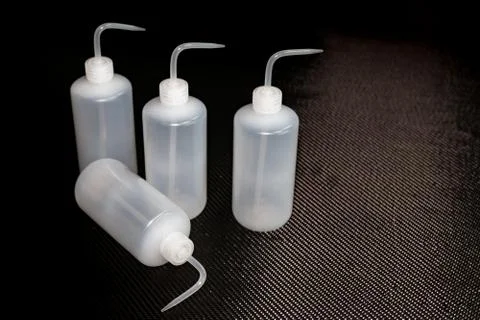 White plastic empty MEKP dispenser bottles on carbon fiber Stock Photos