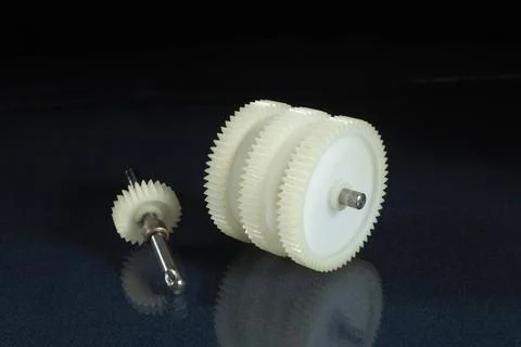 A white plastic gear on a table with a reflection. Stock Photos