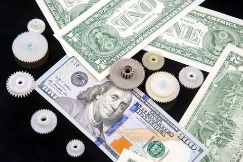 White plastic gears on the background of dollars. financial mechanism of the  Stock Photos