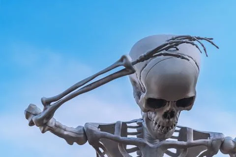 White plastic human skeleton prop raised arm against clear blue sky backgro.. Stock Photos